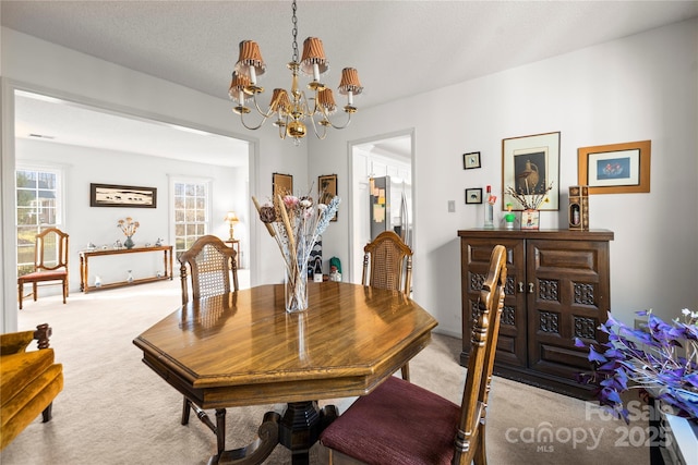 dining space with light colored carpet, a textured ceiling, and an inviting chandelier