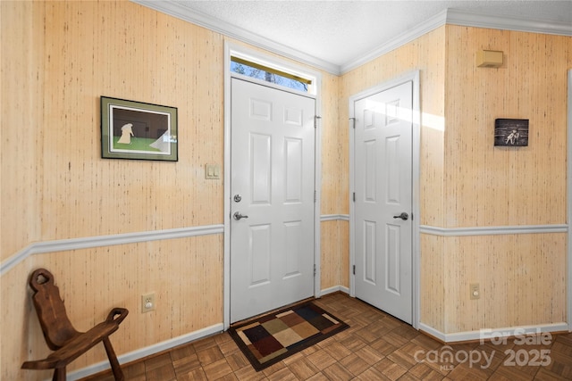 entrance foyer with a textured ceiling, crown molding, wood walls, baseboards, and wallpapered walls