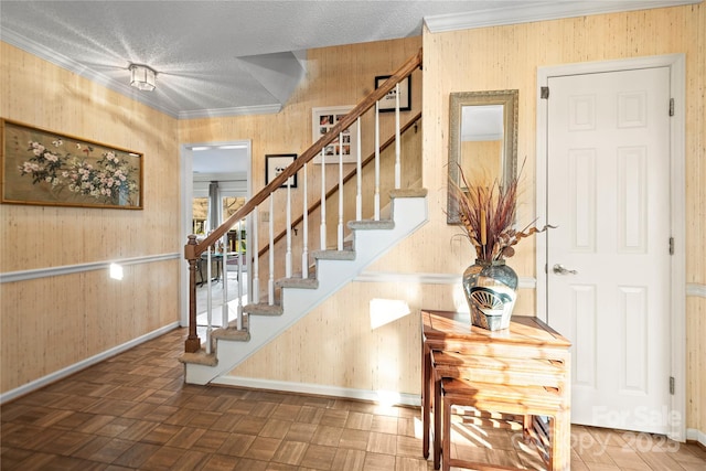 foyer entrance with baseboards, stairs, ornamental molding, and a textured ceiling