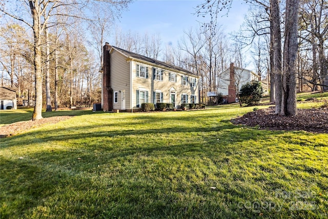 view of front of home featuring central AC, a chimney, and a front yard