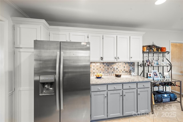 kitchen featuring light tile patterned flooring, gray cabinets, backsplash, stainless steel fridge, and crown molding