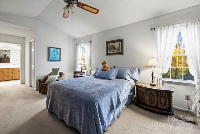 bedroom with light carpet, visible vents, lofted ceiling, ensuite bath, and a textured ceiling