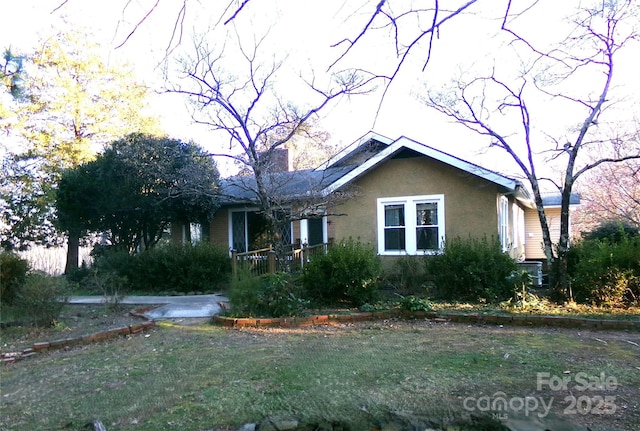 view of front of property featuring a front lawn, a chimney, and stucco siding