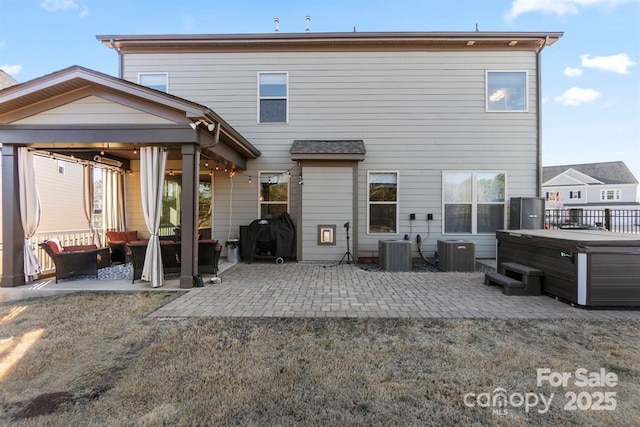 back of house with a hot tub, central AC, and a patio