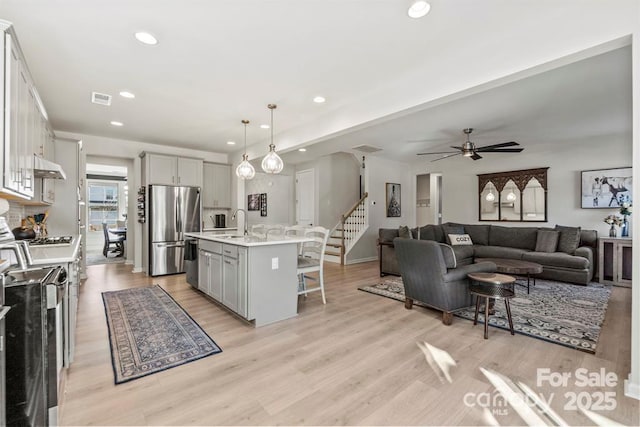 kitchen with stainless steel appliances, a breakfast bar, gray cabinets, and light countertops