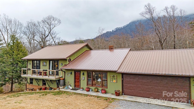 view of front of home featuring a chimney, metal roof, a mountain view, a garage, and driveway