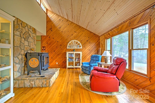 living area featuring a wood stove, wood walls, wood ceiling, and hardwood / wood-style floors