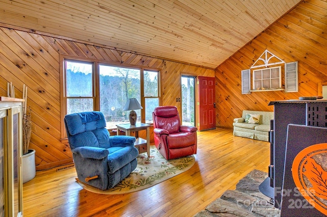 living room featuring lofted ceiling, wood-type flooring, visible vents, wood walls, and wooden ceiling