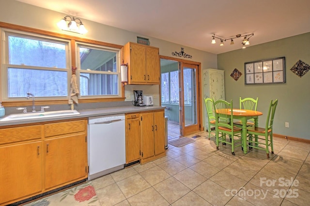 kitchen featuring light tile patterned floors, a sink, baseboards, light countertops, and dishwasher