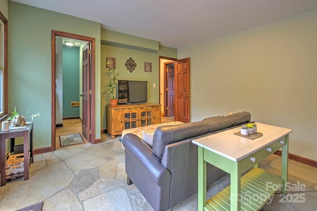 living room featuring baseboards and stone finish floor