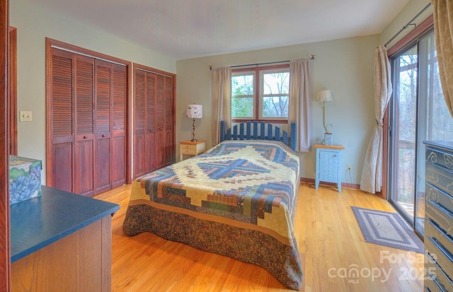 bedroom featuring multiple closets, multiple windows, light wood-style flooring, and baseboards