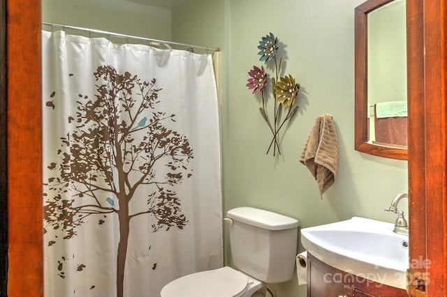 bathroom with curtained shower, vanity, and toilet