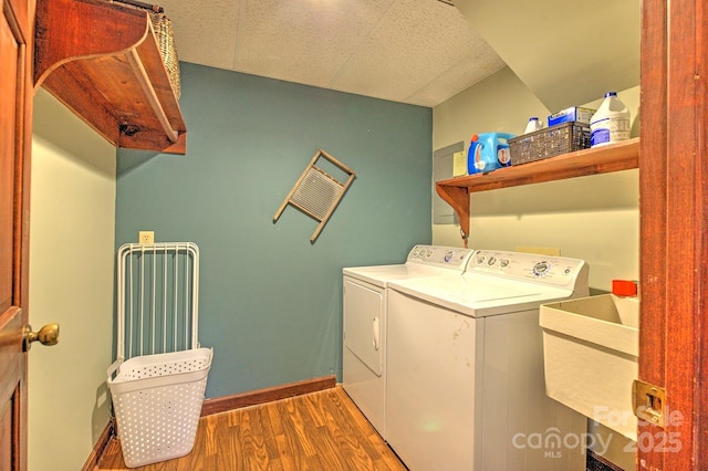 washroom with laundry area, baseboards, wood finished floors, independent washer and dryer, and a sink