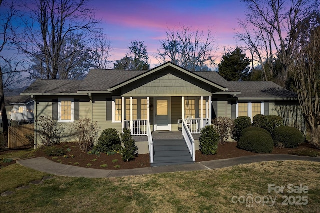 bungalow with a porch and roof with shingles