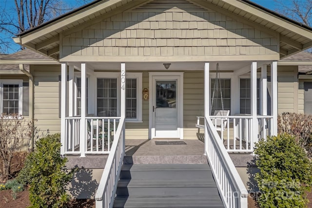 doorway to property with a porch and roof with shingles