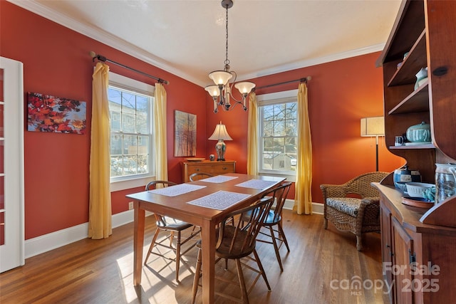 dining room with a notable chandelier, ornamental molding, wood finished floors, and baseboards