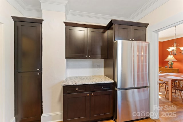 kitchen featuring crown molding, backsplash, freestanding refrigerator, and dark brown cabinetry