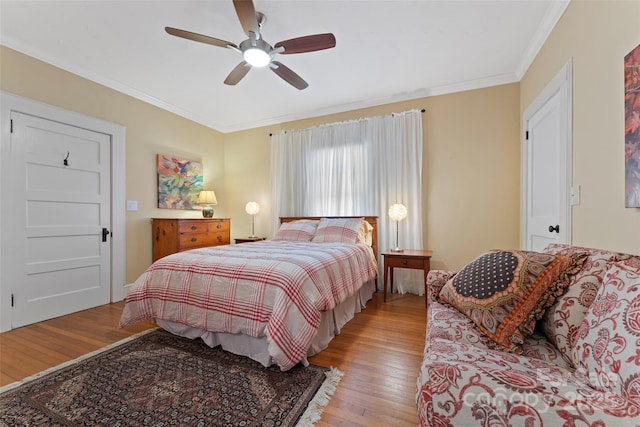 bedroom featuring hardwood / wood-style flooring, ornamental molding, and a ceiling fan