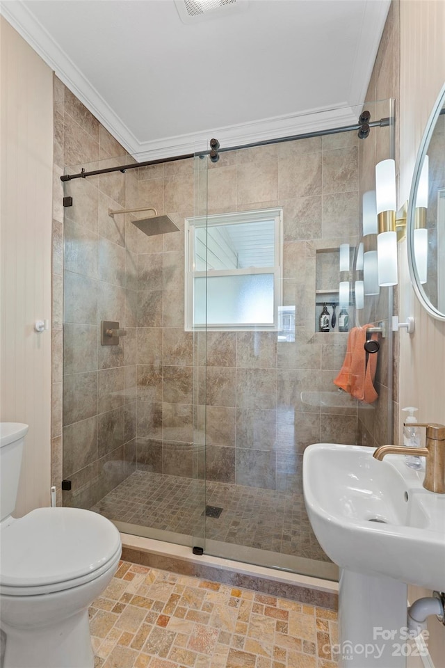 bathroom with a sink, a shower stall, toilet, and crown molding