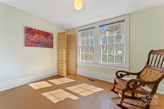 living area featuring visible vents, baseboards, and hardwood / wood-style flooring