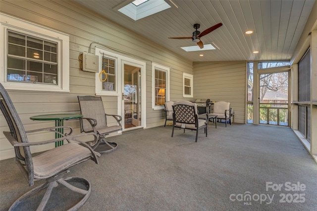 sunroom / solarium featuring a skylight, wooden ceiling, and a ceiling fan