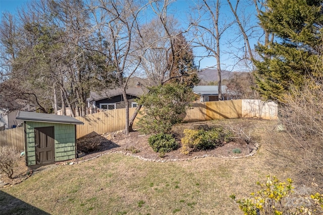 view of yard featuring an outbuilding, a fenced backyard, and a storage shed