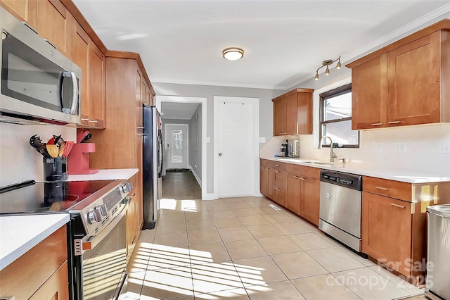 kitchen with brown cabinetry, light countertops, stainless steel appliances, a sink, and light tile patterned flooring