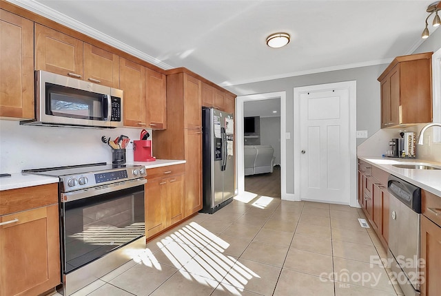 kitchen featuring brown cabinets, stainless steel appliances, light countertops, light tile patterned flooring, and a sink