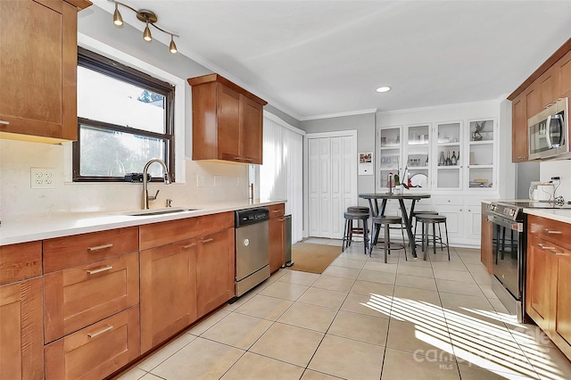 kitchen with light tile patterned floors, brown cabinetry, stainless steel appliances, light countertops, and a sink