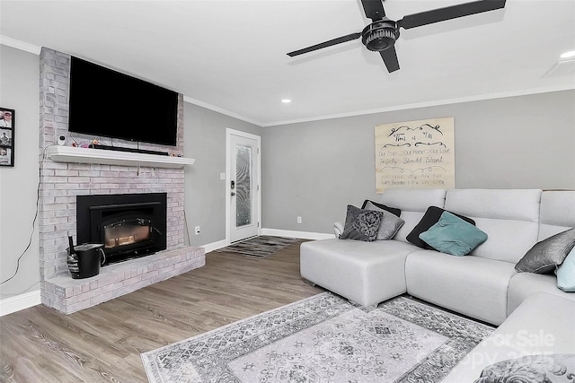 living area featuring ornamental molding, a brick fireplace, baseboards, and wood finished floors