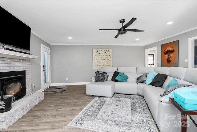 living room featuring a brick fireplace, crown molding, light wood-style flooring, and baseboards