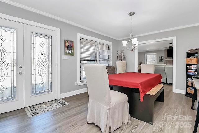 dining space with a healthy amount of sunlight, crown molding, an inviting chandelier, and wood finished floors