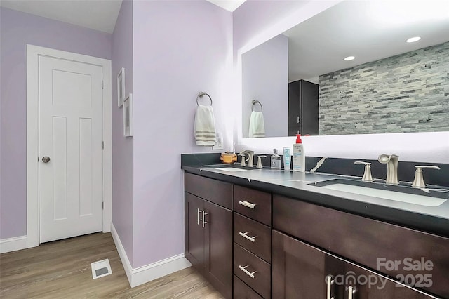 full bath featuring double vanity, wood finished floors, a sink, and visible vents