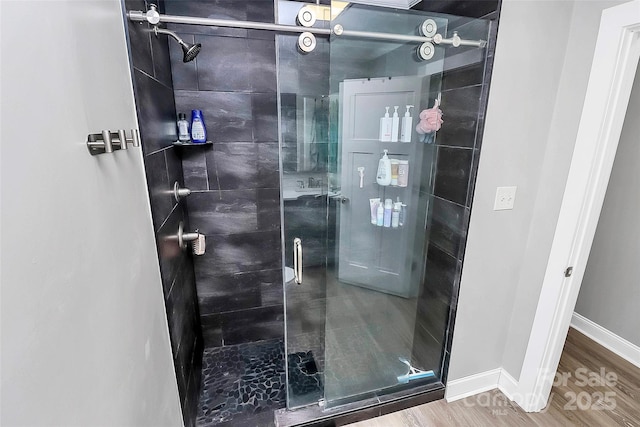 full bath with wood finished floors, a shower stall, and baseboards