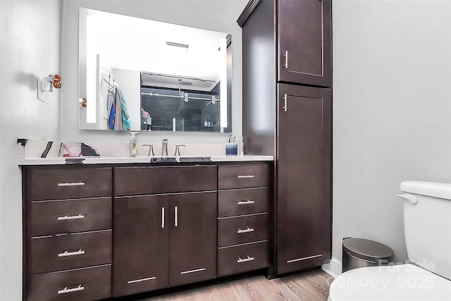 bathroom with toilet, wood finished floors, and vanity