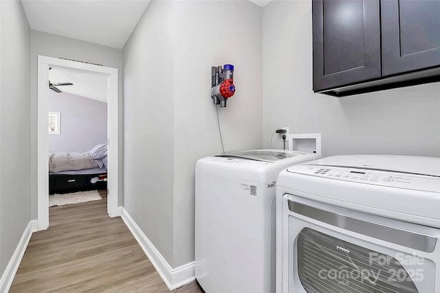 laundry area with light wood finished floors, washing machine and dryer, cabinet space, and baseboards