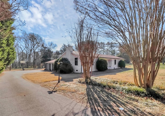 view of front of home featuring driveway, a chimney, and stucco siding