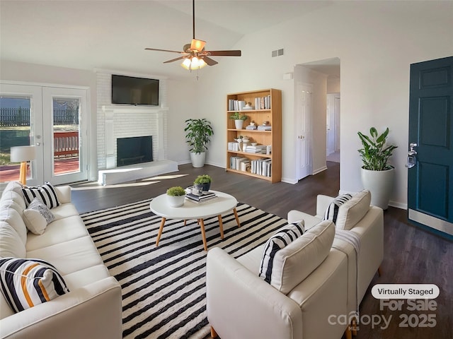 living room featuring visible vents, vaulted ceiling, a fireplace, and wood finished floors