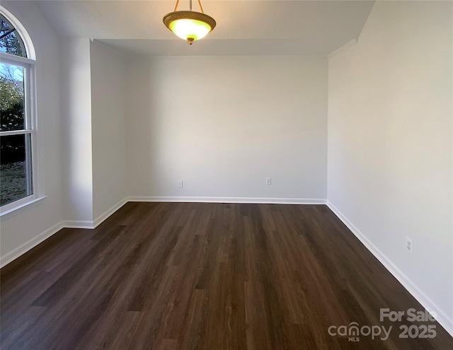 empty room with dark wood finished floors and baseboards