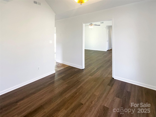 empty room with dark wood-style floors, visible vents, baseboards, and a ceiling fan