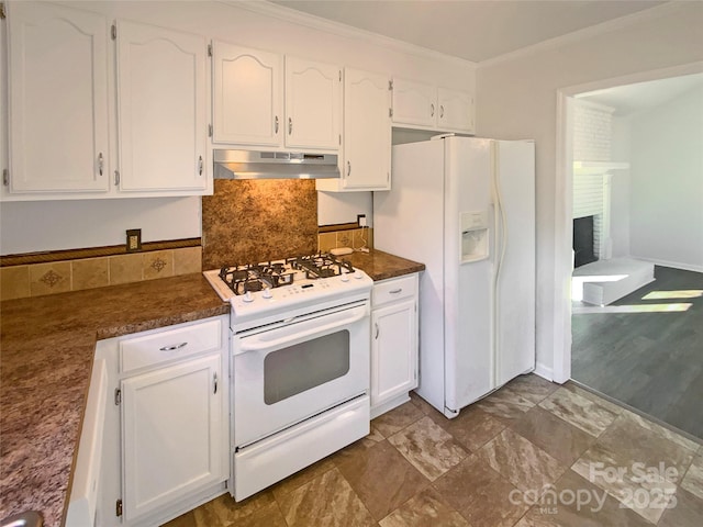 kitchen with white appliances, white cabinets, dark countertops, crown molding, and under cabinet range hood