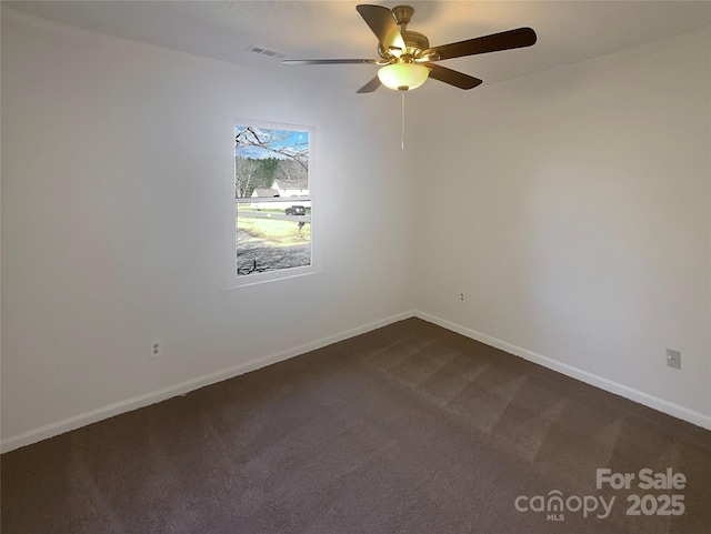 spare room featuring dark carpet, visible vents, and baseboards