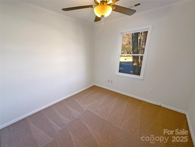 carpeted empty room featuring baseboards, visible vents, a ceiling fan, and ornamental molding