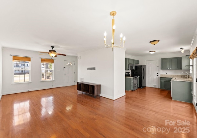 unfurnished living room featuring ornamental molding, a sink, light wood-style flooring, and baseboards