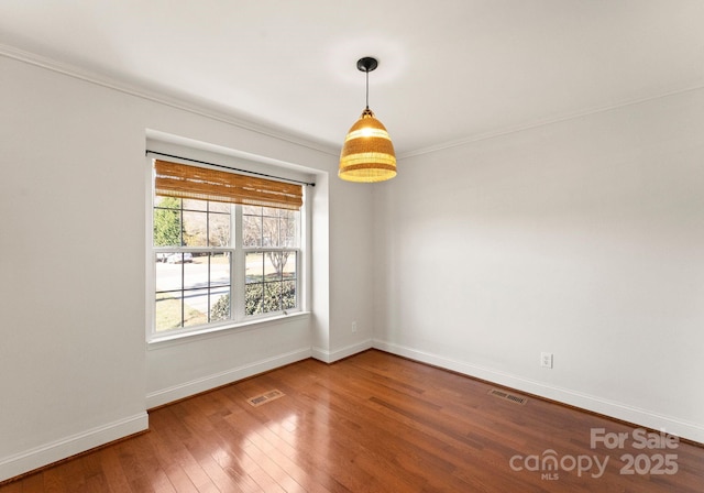 unfurnished room featuring visible vents, crown molding, baseboards, and hardwood / wood-style flooring