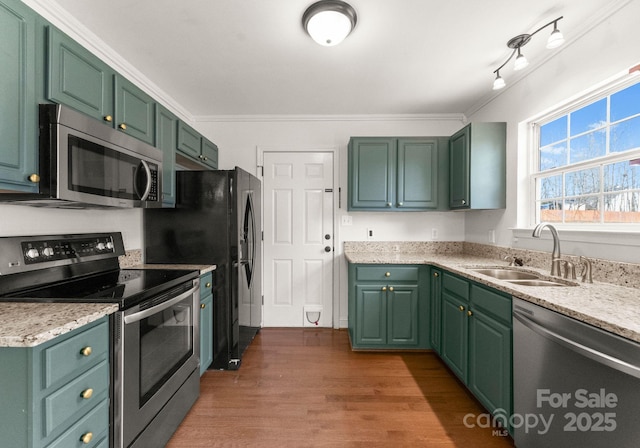 kitchen featuring dark wood-style flooring, crown molding, appliances with stainless steel finishes, a sink, and light stone countertops