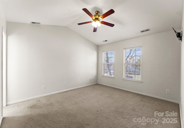 carpeted empty room with visible vents, vaulted ceiling, and baseboards