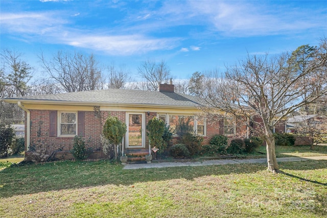 view of front of property featuring a front lawn, a chimney, a shingled roof, and brick siding