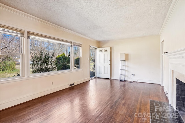 unfurnished living room with ornamental molding, a textured ceiling, a tiled fireplace, and wood finished floors