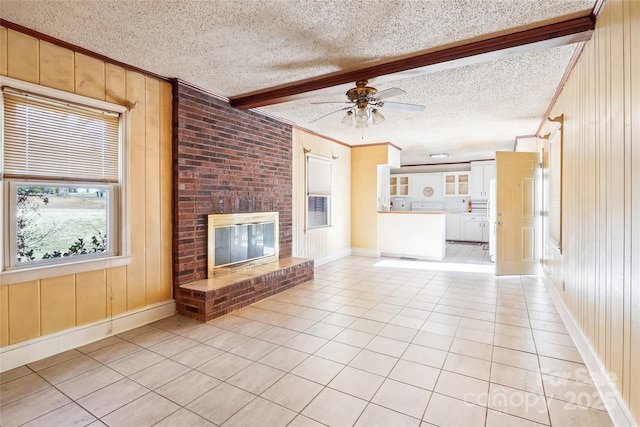 unfurnished living room with beam ceiling, a fireplace, light tile patterned flooring, wooden walls, and a textured ceiling